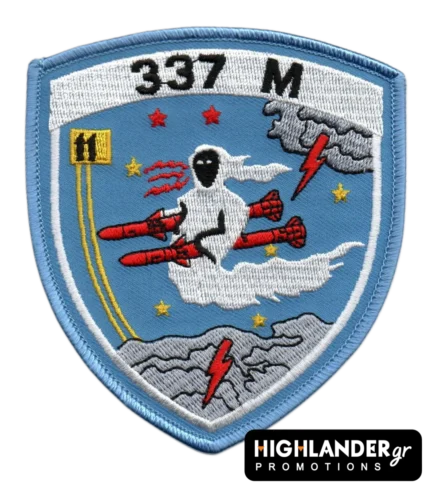 Cyan embroidered patch with ghost riding red missiles, stars, clouds, yellow squadron emblem, "337 M" text, and blue border.