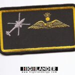 Embroidered patch with silver helicopter silhouette and gold pilot wings with crown and sun on black background, yellow border.