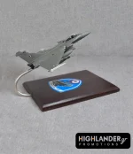 Desktop scale model of a Hellenic Air Force Rafale fighter jet mounted on a wooden base. The base features the HTAF (ATA) eagle emblem.
