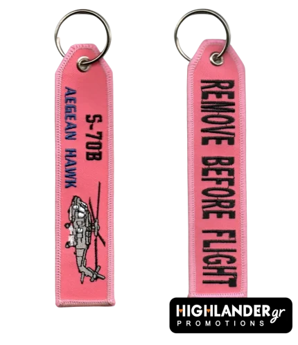 Ροζ κεντητό μπρελόκ αεροπορίας S-70B Aegean Hawk. Η μία πλευρά δείχνει το ελικόπτερο και κείμενο. Η άλλη γράφει "REMOVE BEFORE FLIGHT" με μαύρα γράμματα.