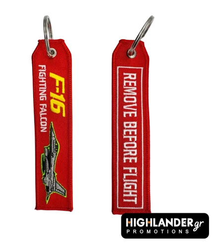 Κόκκινο κεντητό μπρελόκ με παράσταση αεροσκάφους F-16 Fighting Falcon και κείμενο Remove Before Flight με λευκά γράμματα.