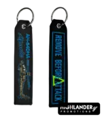 Black embroidered keychain showing AH-64DHA Apache helicopter on one side and Remove Before Attack text in blue on the other side.