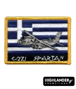 Rectangular tactical patch featuring a C-27J Spartan aircraft embroidered over a Greek flag with white and blue stripes. Bottom text reads "C-27J SPARTAN" in ancient-style font.