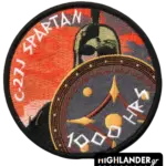 Round embroidered patch with an orange sunset background. Features a Spartan warrior holding a shield, with text "C-27J SPARTAN" and "1000 HRS".