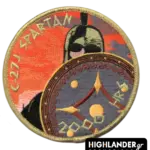 Round embroidered patch with gold border. Features a Spartan warrior and shield against an orange sunset background with gold text "C-27J SPARTAN" and "2000 HRS".