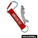 Aviation keychain combo set. Features a grey 3D PVC C-27J Spartan aircraft figure and a red "Remove Before Flight" fabric tag, attached together with a metal carabiner.