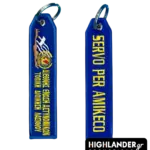 Blue embroidered keychain for IPA Lasithi. Side A shows the map of Crete, Greek flag, and Greek text. Side B shows the motto "SERVO PER AMIKECO" in yellow letters.