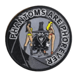 Circular embroidered patch with the text "PHANTOMS ARE PHOREVER". The center features the F-4 Phantom Spook mascot standing between two women in bikinis against a grey background.