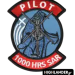 Embroidered aviation patch with red top and bottom tabs. Top reads "PILOT", bottom reads "1000 HRS SAR". Center shows a Super Puma helicopter on a blue background.