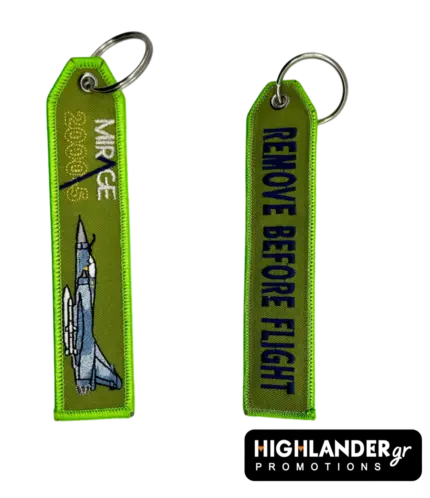 Olive green embroidered keychain from Highlander Promotions. Side A: Mirage 2000-5 aircraft and text. Side B: "REMOVE BEFORE FLIGHT" in dark blue lettering.