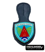 This dark blue leather badge hanger features a shield-shaped enamel badge with a vibrant light blue background, a prominent red arrowhead insignia, and radiating yellow stripes, all outlined in a metallic finish. Designed as an official holder for the 116 Combat Wing, it proudly displays the Greek motto "Para Dynamin Tolmitai," offering a distinguished utility for military personnel to showcase unit affiliation.
