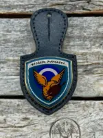 A navy blue leather badge holder featuring the 114 Combat Wing enamel crest with an eagle, a shield, and the Greek motto "Fylakis Mnisasthe".