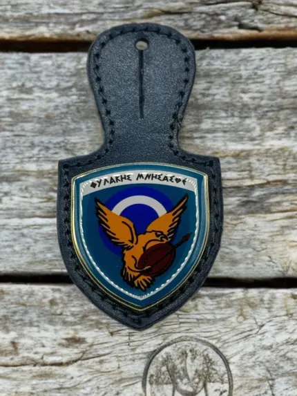 A navy blue leather badge holder featuring the 114 Combat Wing enamel crest with an eagle, a shield, and the Greek motto "Fylakis Mnisasthe".