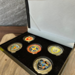 Black velvet-lined presentation box containing five gold-tone military challenge coins from various Hellenic Air Force and Army Aviation units.