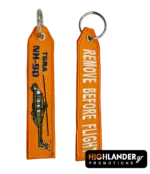 Orange embroidered keychain for NH-90 TGRA helicopter from Highlander Promotions. Side A shows the helicopter graphic and yellow text. Side B shows "REMOVE BEFORE FLIGHT".