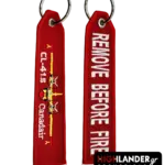 Red fabric keychain with embroidered CL-415 Canadair aircraft on one side and white "REMOVE BEFORE FIRE" text on the other.