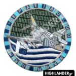 Round blue and silver embroidered military morale patch showing an F-4E Phantom jet over the Greek flag with a digital binary code background.